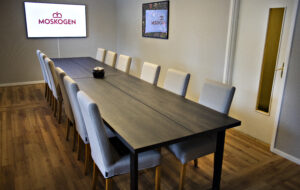 Konferensrum Prästkragen – bord med 12 stolar. TV-skärm på väggen.